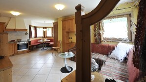 A kitchen with wooden cabinets, a dining table, and a window with curtains.