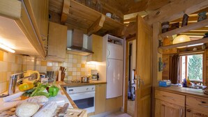 Een houten keuken met een witte koelkast, houten kastjes en een betegelde spatwand.