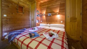 Een houten kamer met een bed, een houten deur en een klein wandlampje.