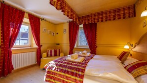 Ett hotellrum med en stor säng, röda gardiner, en sänggavel i trä och ett fönster med utsikt.