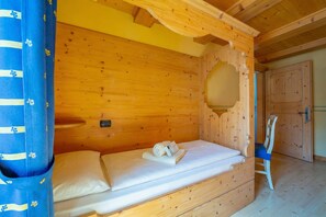 A wooden cabin room with a bed, a chair, and a door. - Smeraldo Ski in, Livigno, Italy (Livigno)