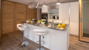 A modern kitchen with a central island, stainless steel appliances, and wooden flooring.