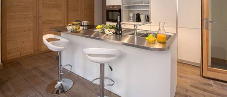 A modern kitchen with a central island, stainless steel appliances, and wooden flooring.