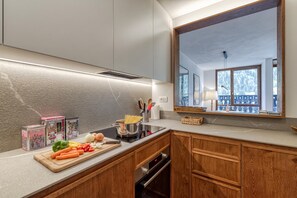 A modern kitchen with a large mirror, wooden cabinets, and a countertop with fresh vegetables. - Androsace 31 Walk to Ski Lifts + Pool & Mont-Blanc View in Argentière, Argentière (Chamonix), France (Argentière (Chamonix))