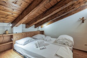 A bedroom with a wooden ceiling, a bed with white linens, a bedside table, and a wall-mounted light fixture. - Androsace 31 Walk to Ski Lifts + Pool & Mont-Blanc View in Argentière, Argentière (Chamonix), France (Argentière (Chamonix))