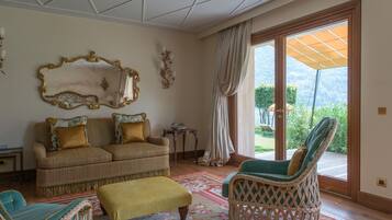 A living room with a sofa, two armchairs, a bench, a large mirror, and a view through a glass door.