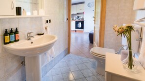 Ein modernes Badezimmer mit Waschbecken, Toilette und einer Blumenvase auf der Ablagefläche.