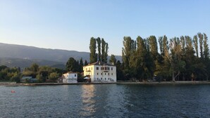 A waterfront property with a large white building, a smaller structure, and tall trees. - PELION HOMES | STONE HOUSE  charming villa with amazing view for 2-4 guests (Agios Georgios Nilias)
