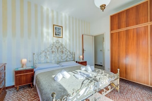 Une chambre à coucher avec un lit, une armoire en bois, une table de chevet avec une lampe et un mur à rayures.