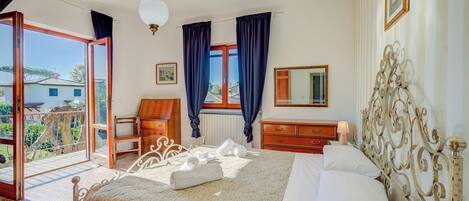 A hotel room with a bed, a chair, a dresser, and a window with curtains.