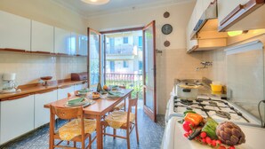 Une cuisine avec des meubles blancs, une cuisinière et une table à manger avec des chaises.