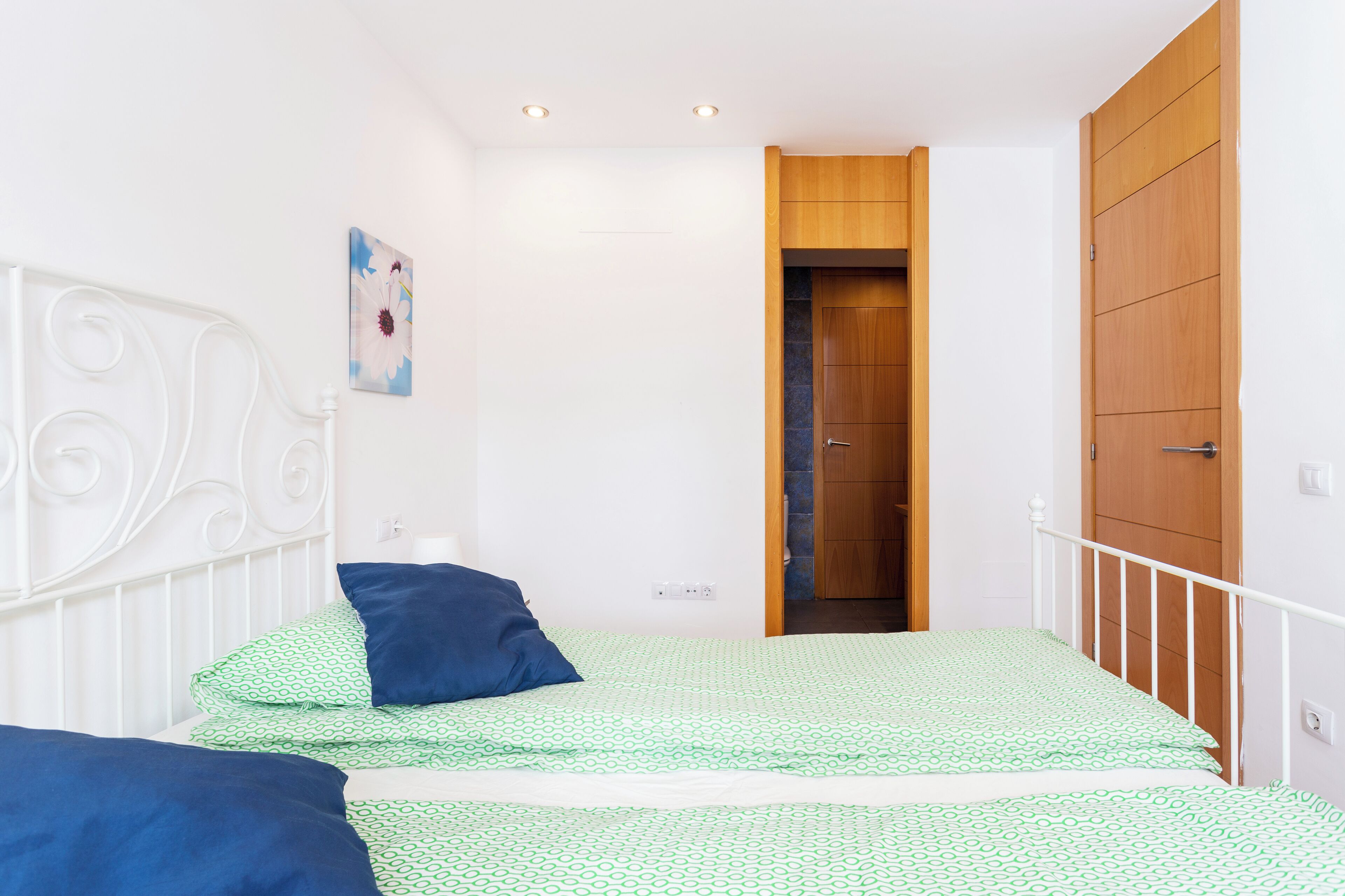 Ein Schlafzimmer mit einem Bett, einem Holzschrank und einer Tür zu einem anderen Raum.