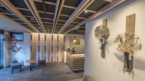 Een modern interieur met een receptiebalie, een zithoek en decoratieve wandkunst.
