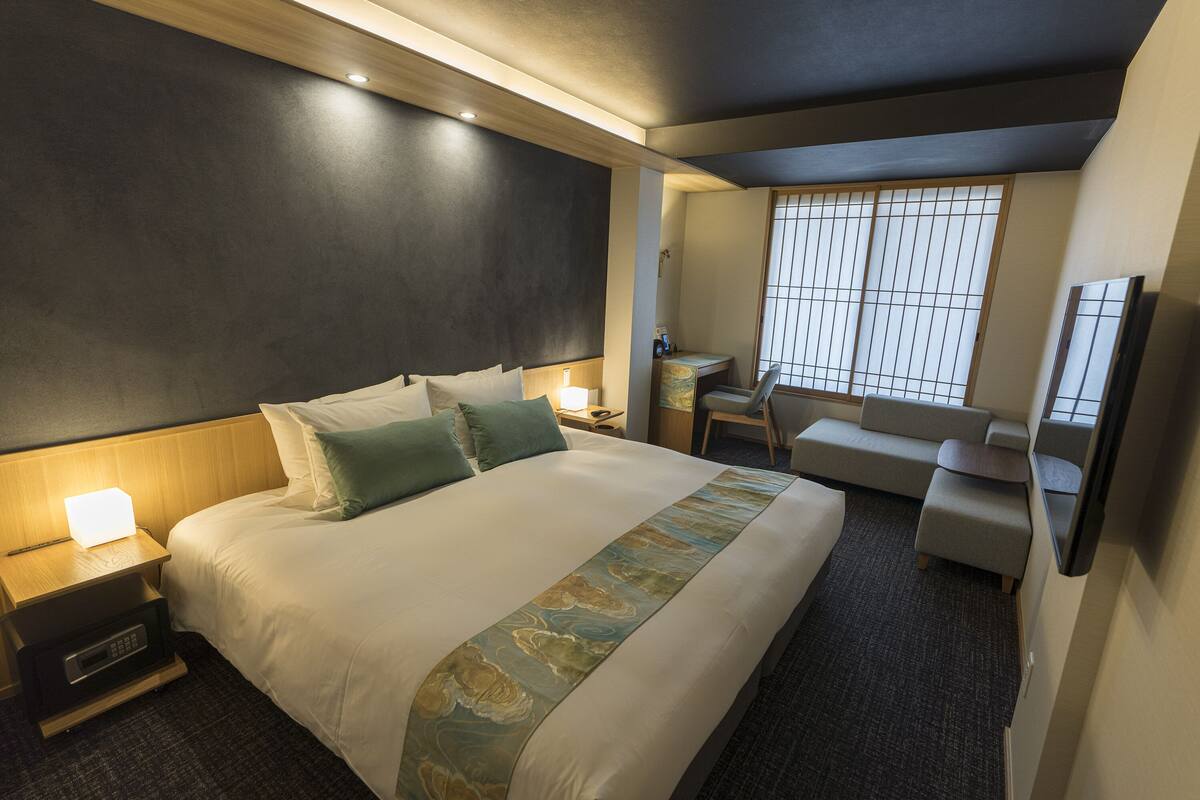 Une chambre d’hôtel avec un grand lit, des tables de chevet, un bureau, une chaise et un téléviseur.