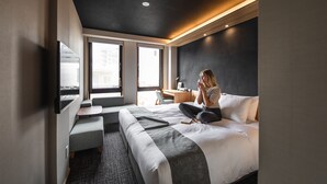 Een moderne hotelkamer met een groot bed, een bureau, een flatscreen televisie en grote ramen.