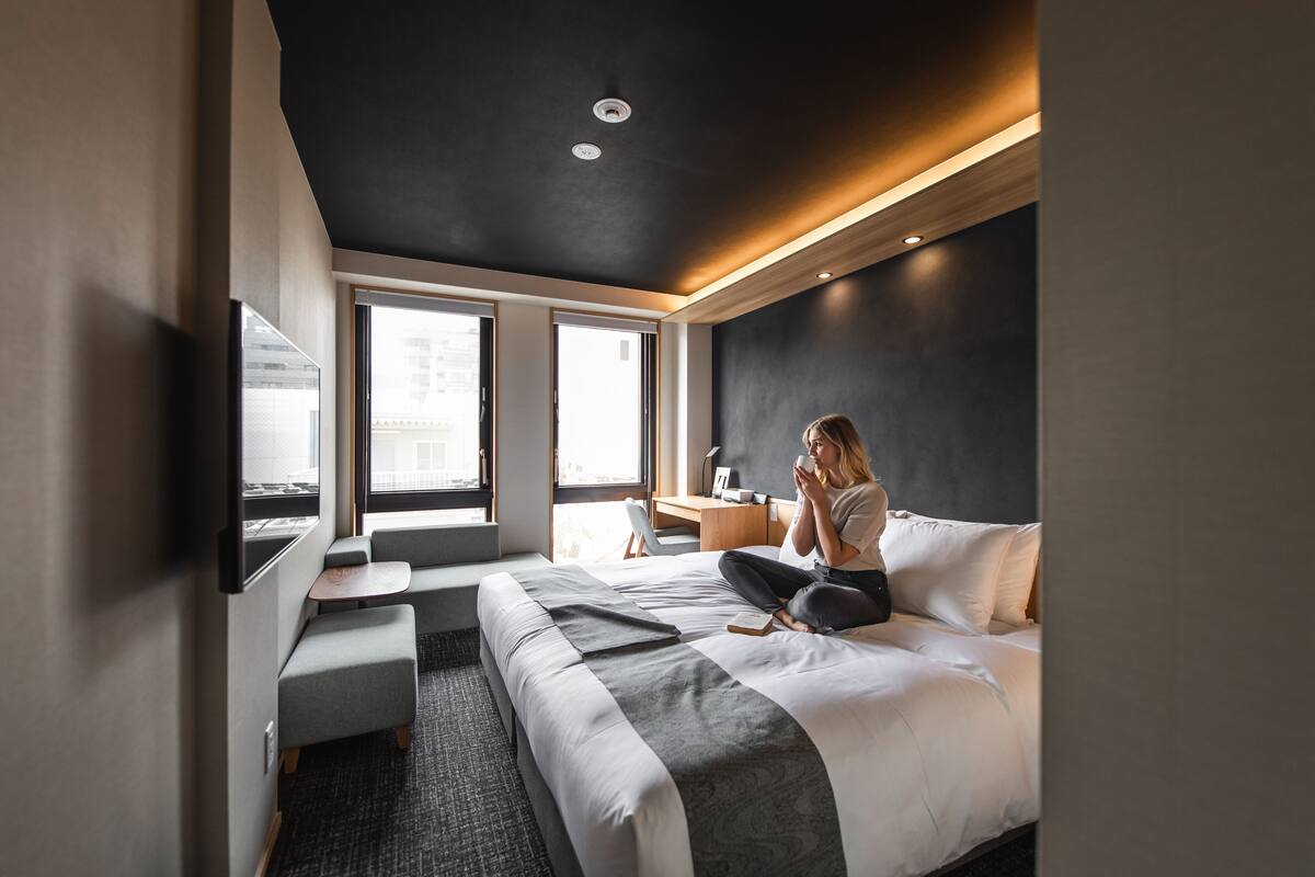Une chambre d’hôtel moderne dotée d’un grand lit, d’un bureau, d’une télévision à écran plat et de grandes fenêtres.
