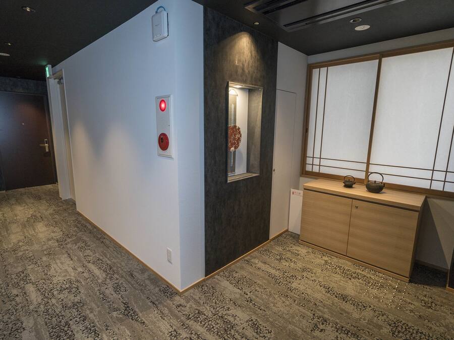 A hallway with a reception desk, a mirror, and a wooden cabinet.