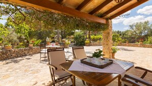 An outdoor patio with wooden tables and chairs, surrounded by stone walls and potted plants. - Son Mulet - Beautiful villa with private pool and garden in Llubí (Llubí)