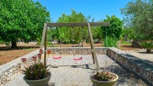 A wooden swing set with two swings, surrounded by a stone pathway and potted plants. - Son Mulet - Beautiful villa with private pool and garden in Llubí (Llubí)