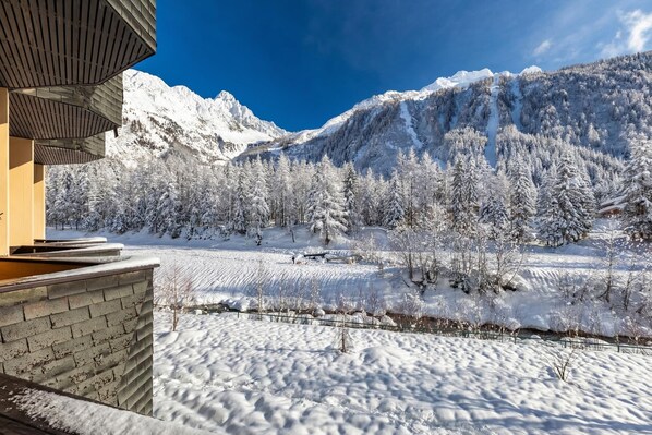 A snow-covered landscape with a mountain in the background and a building with a sloped roof.