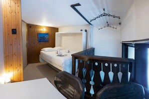 A room with a bed, a desk, a chair, a wooden panel wall, a painting, and a hanging light fixture. - Grand Roc C114 280m from Slopes, View, Parking & WiFi, Argentière (Chamonix), France (Argentière (Chamonix))