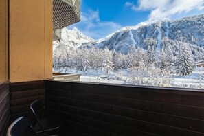 A balcony with a view of snow-covered mountains and trees.