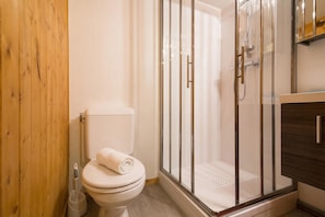 A bathroom with a toilet, a glass-enclosed shower, and wooden paneling. - Grand Roc C114 280m from Slopes, View, Parking & WiFi, Argentière (Chamonix), France (Argentière (Chamonix))