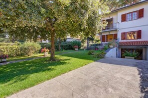 Un immeuble de deux étages doté d’un jardin, d’une allée pavée et d’un balcon.