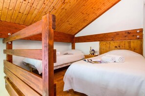 Habitación con dos camas literas de madera, una mesita de noche y una revista sobre una de las camas.