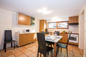 Cocina compacta con comedor, equipada con microondas, estufa y ventana que proporciona luz natural.