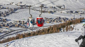 Een kabelbaan systeem met kabinetten dat zich verplaatst boven een besneeuwd landschap.