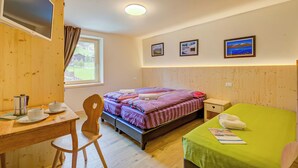 Een kamer met een bed, bureau, stoel, televisie en raam.