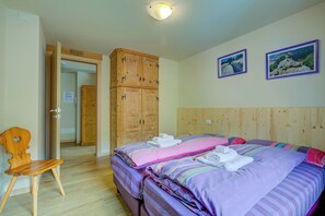 Une chambre avec deux lits, une armoire en bois et deux tableaux encadrés accrochés au mur.