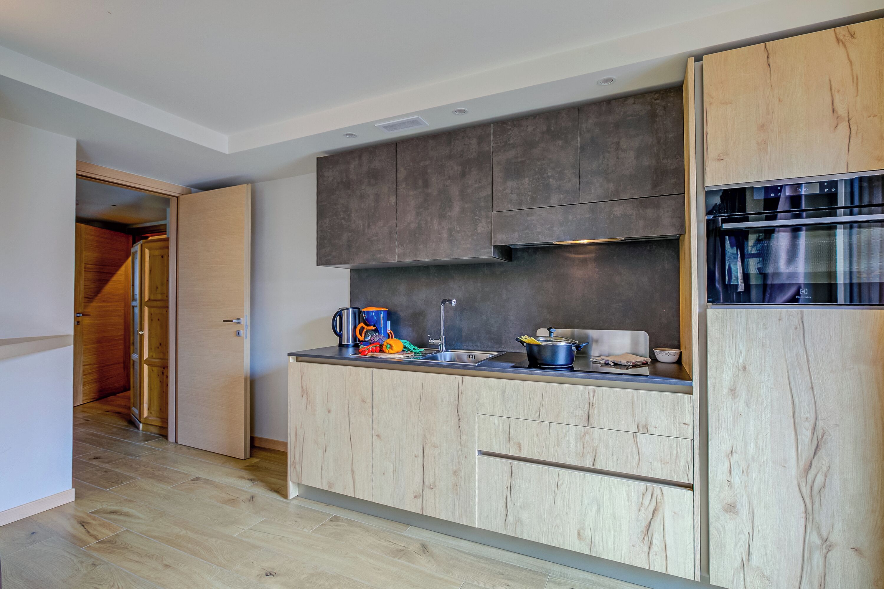 Eine moderne Küche mit Holzausstattung, einem eingebauten Ofen und einer Arbeitsplatte mit verschiedenen Küchenutensilien.