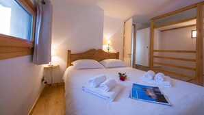 A neatly made bed with rolled towels, a bedside lamp, and a magazine on the bed. - Grand Roc B121 260m from Slopes, View & Parking, Argentière (Chamonix), France (Argentière (Chamonix))
