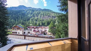 A wooden balcony with a view of a mountain, a building with a red roof, and a parking area. - Grand Roc B121 260m from Slopes, View & Parking, Argentière (Chamonix), France (Argentière (Chamonix))