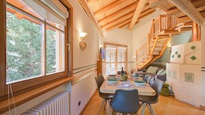 A wooden interior with a dining table, chairs, a staircase, and a view of trees through large windows. - Bucaneve, Livigno, Italy (Livigno)