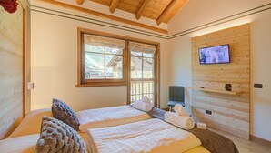 A room with two beds, a television, and a window with curtains. - Bucaneve, Livigno, Italy (Livigno)