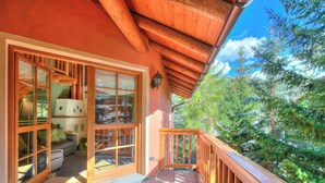 A wooden balcony with a view of trees, a sliding glass door leading to a room with a sofa and a lamp, and a wooden ceiling. - Bucaneve, Livigno, Italy (Livigno)