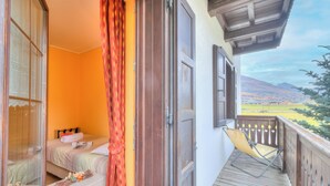 A balcony with a wooden floor, a chair, and a bed with a window. - Stella Alpina, Livigno, Italy (Livigno)