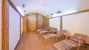 A room with wooden walls and ceiling, a sloped ceiling, and several wooden chairs arranged in rows. - Stella Alpina, Livigno, Italy (Livigno)