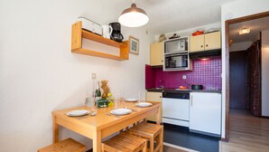A compact kitchen with a wooden table, bench seating, a microwave, and a toaster. - La Verte 12 Ski In/Ski Out | Grands Montets | Argentière Chamonix, Argentière (Chamonix), France (Argentière (Chamonix))