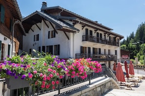 Ein traditionelles Gebäude mit Balkonen, Blumenarrangements und Außenbestuhlung.