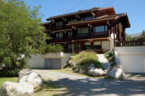 Ein mehrstöckiges Holzgebäude mit Balkonen, einer Garage und einer Auffahrt mit großen Steinen.