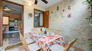 Un comedor con una mesa dispuesta para cuatro, un ventilador de techo y una pared de piedra con adornos.