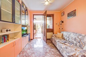 A living room with a sofa, a television, and a bookshelf. - Residenza Verde - 3 Pools & Garage, Desenzano Del Garda, Italy (Desenzano Del Garda)