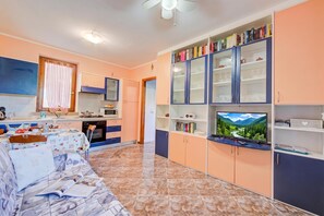 A living room with a sofa, a television, and a bookshelf filled with books and decorative items. - Residenza Verde - 3 Pools & Garage, Desenzano Del Garda, Italy (Desenzano Del Garda)
