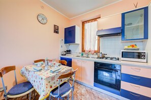 A compact kitchen with a dining area, featuring a stove, microwave, sink, and a clock on the wall. - Residenza Verde - 3 Pools & Garage, Desenzano Del Garda, Italy (Desenzano Del Garda)