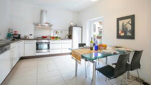 Una cocina moderna con armarios blancos, electrodomésticos de acero inoxidable y una mesa de comedor de vidrio.