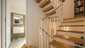 A modern staircase with wooden steps and white railings, leading to a bathroom with a mirror and a sink. - Ca' Melin with Balcony & Fireplace, Vezio, Switzerland (Vezio)